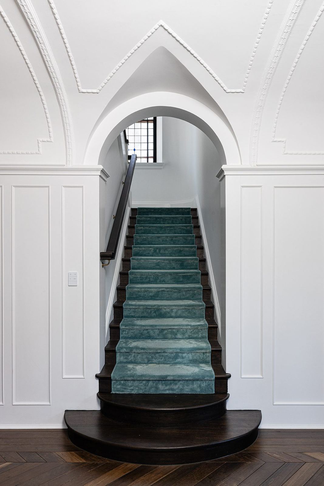 Bellevue Hill — curved timber staircase in a white arched stairwell with teal carpet, built by HP Constructions with Foster & Associates