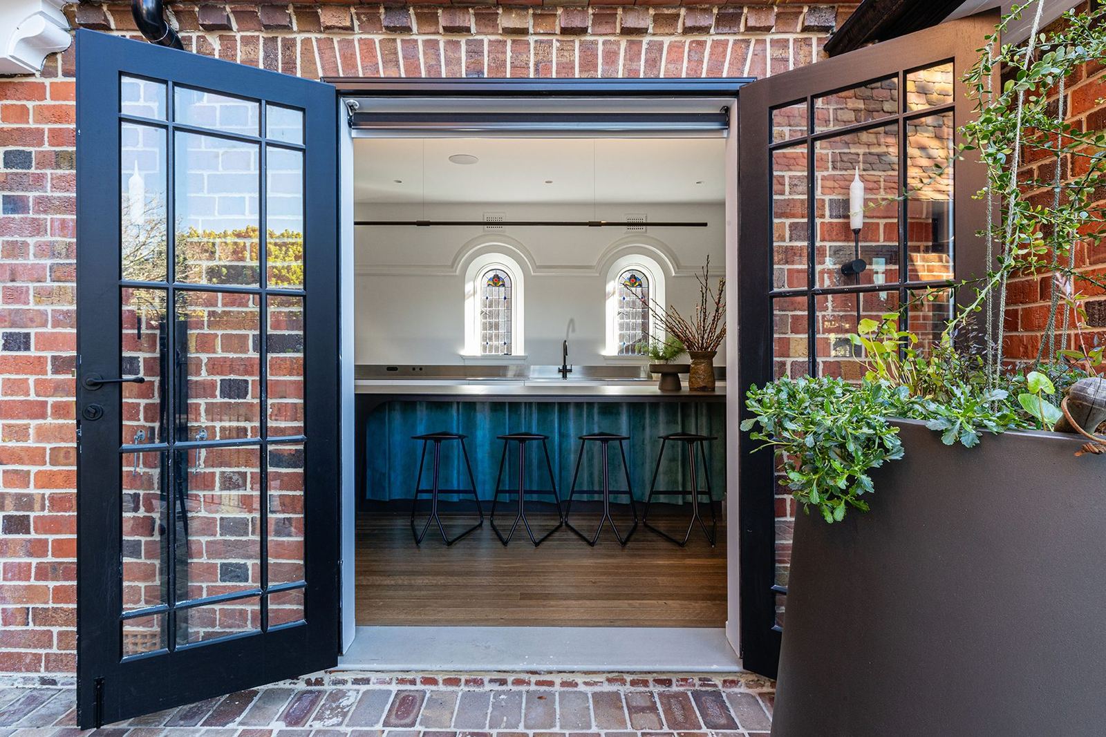 Bellevue Hill — black steel-framed glass doors in a red-brick wall opening onto a kitchen, built by HP Constructions with Foster & Associates