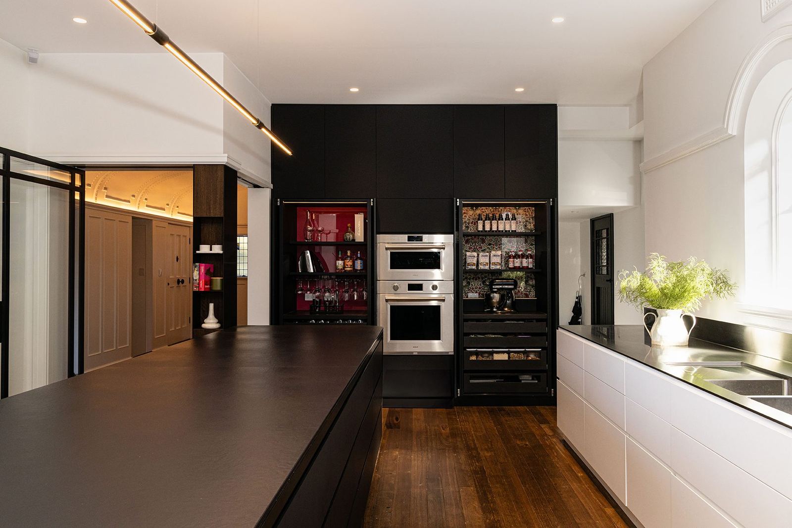 Bellevue Hill — long dark stone kitchen island with black cabinetry, wall ovens and timber floor, built by HP Constructions with Foster & Associates