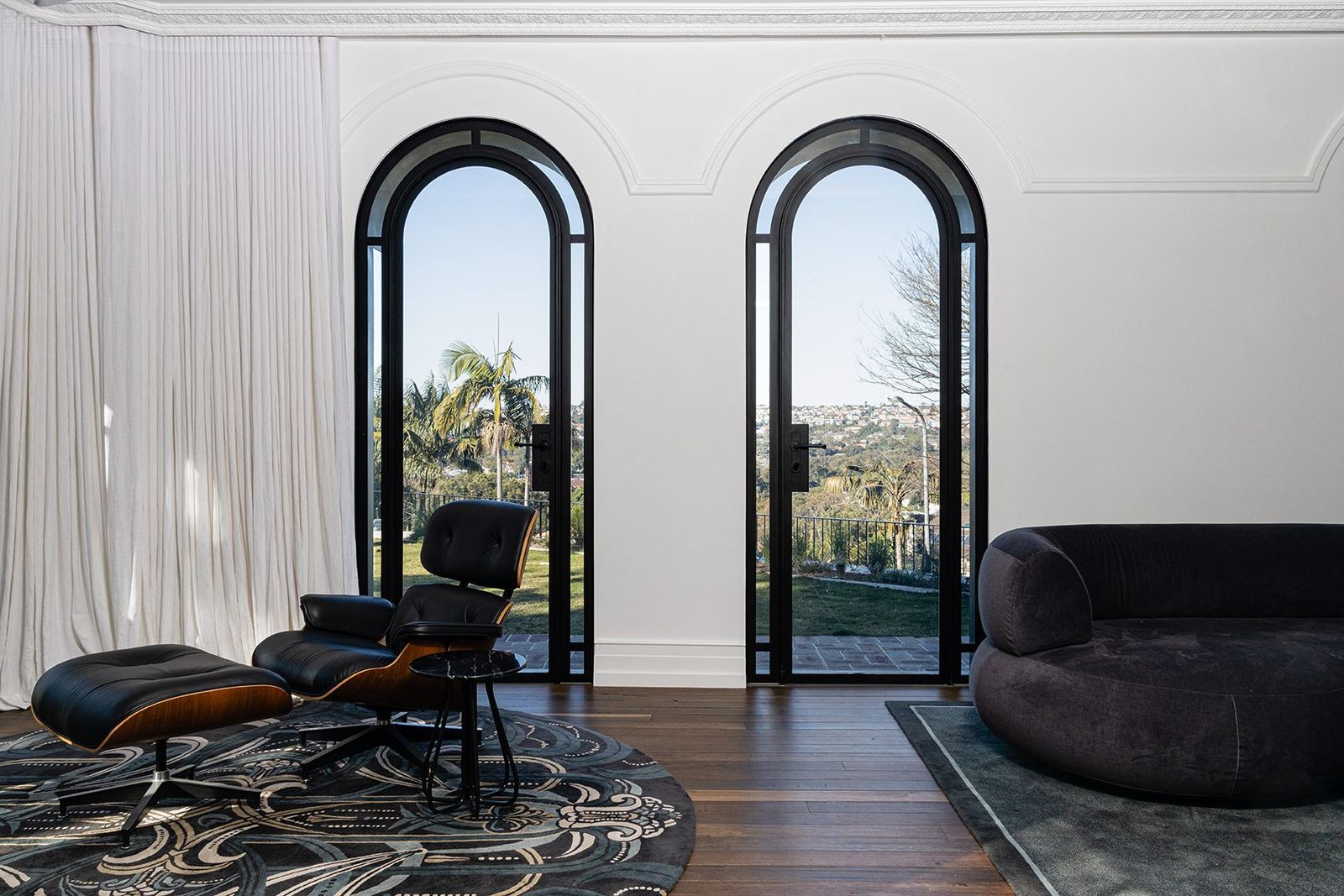 Bellevue Hill — living room with twin arched steel doors, Eames lounge chair and patterned rug, built by HP Constructions with Foster & Associates