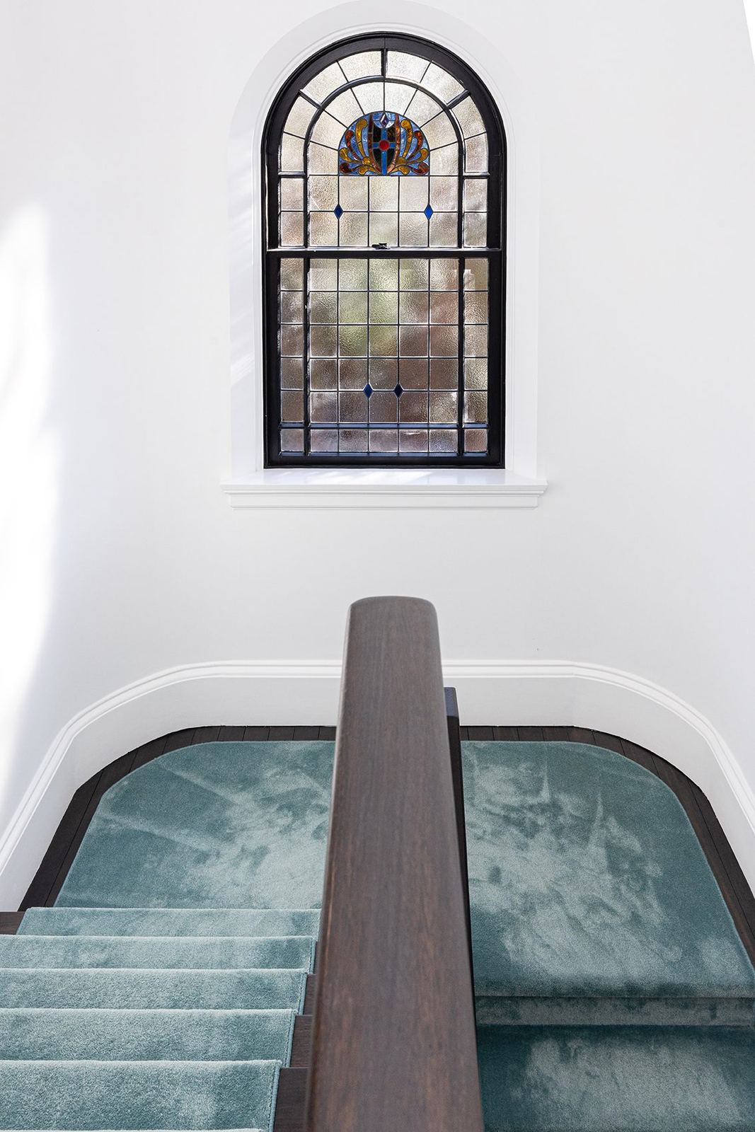 Bellevue Hill — curved staircase with teal carpet beneath an arched stained-glass window, built by HP Constructions with Foster & Associates