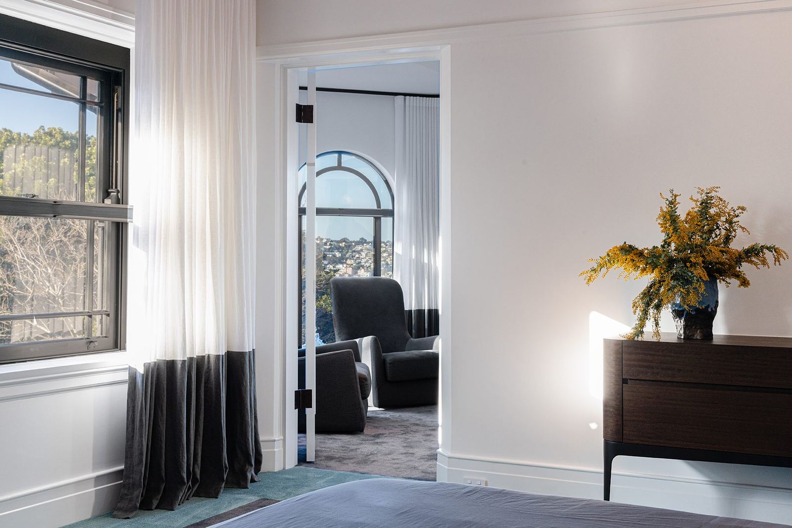 Bellevue Hill — carpeted bedroom with arched window, sheer curtains and dark timber sideboard, built by HP Constructions with Foster & Associates