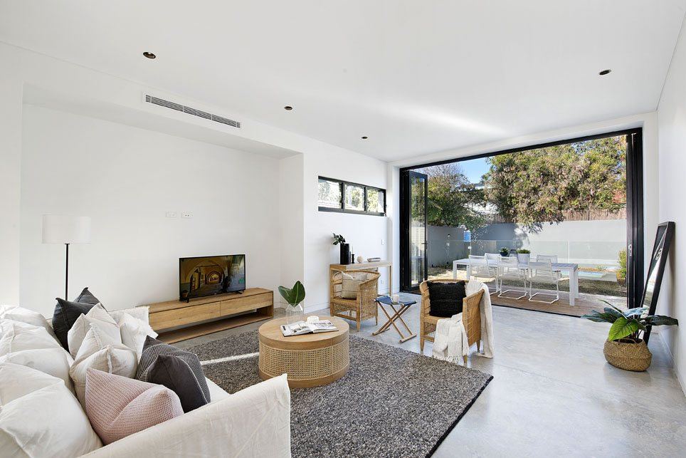 Bondi — living room with sofa, timber unit and glass door to terrace, built by HP Constructions with Arkhaus