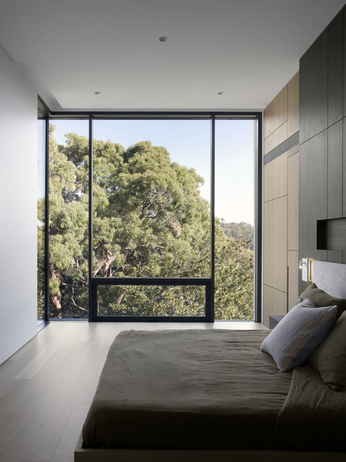 Castle Cove — bedroom with corner glazing framing treetop views, built by HP Constructions with Dieppe Design