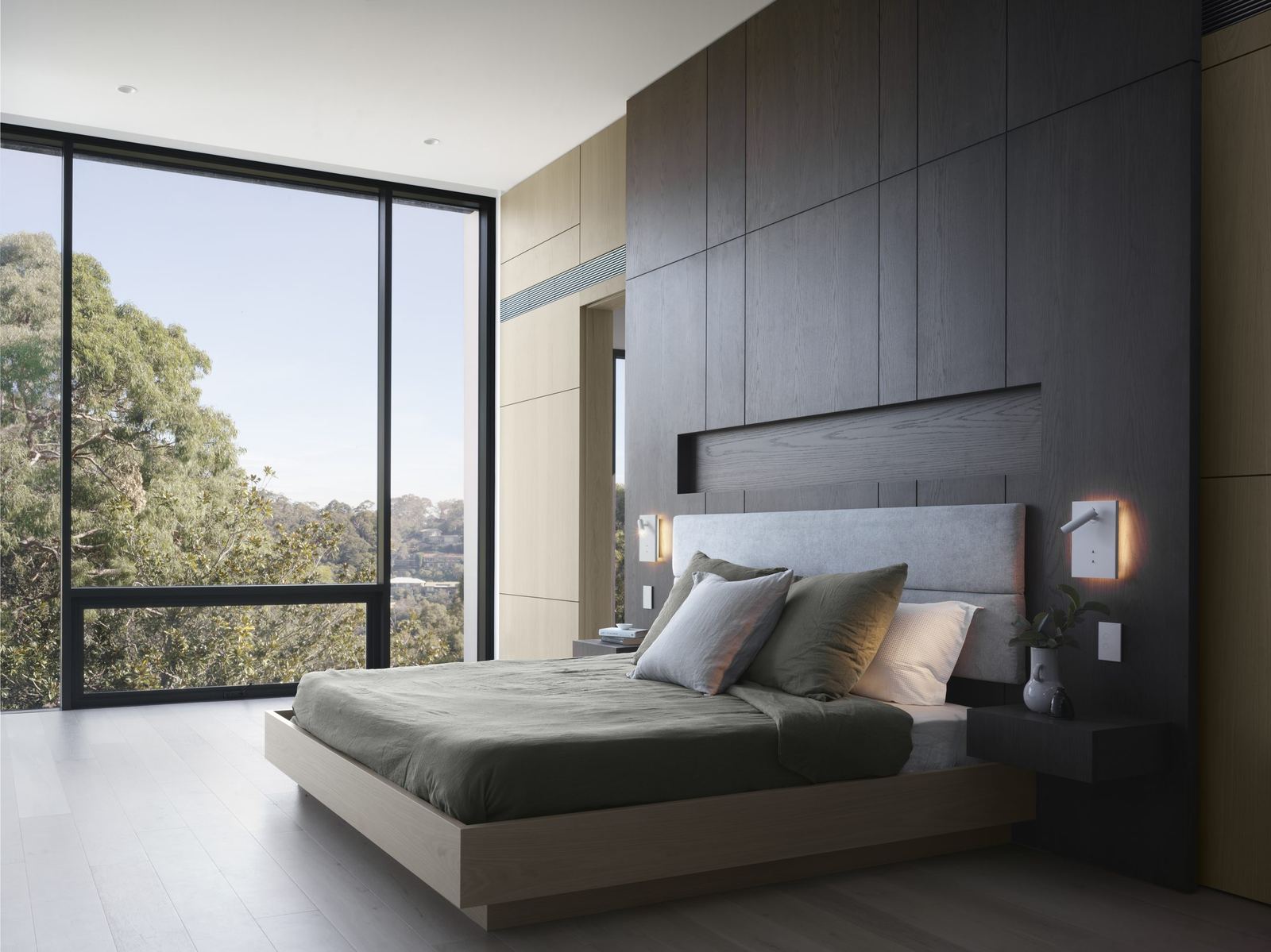 Castle Cove — bedroom with dark timber wall, green bedding and corner glazing to trees, built by HP Constructions with Dieppe Design