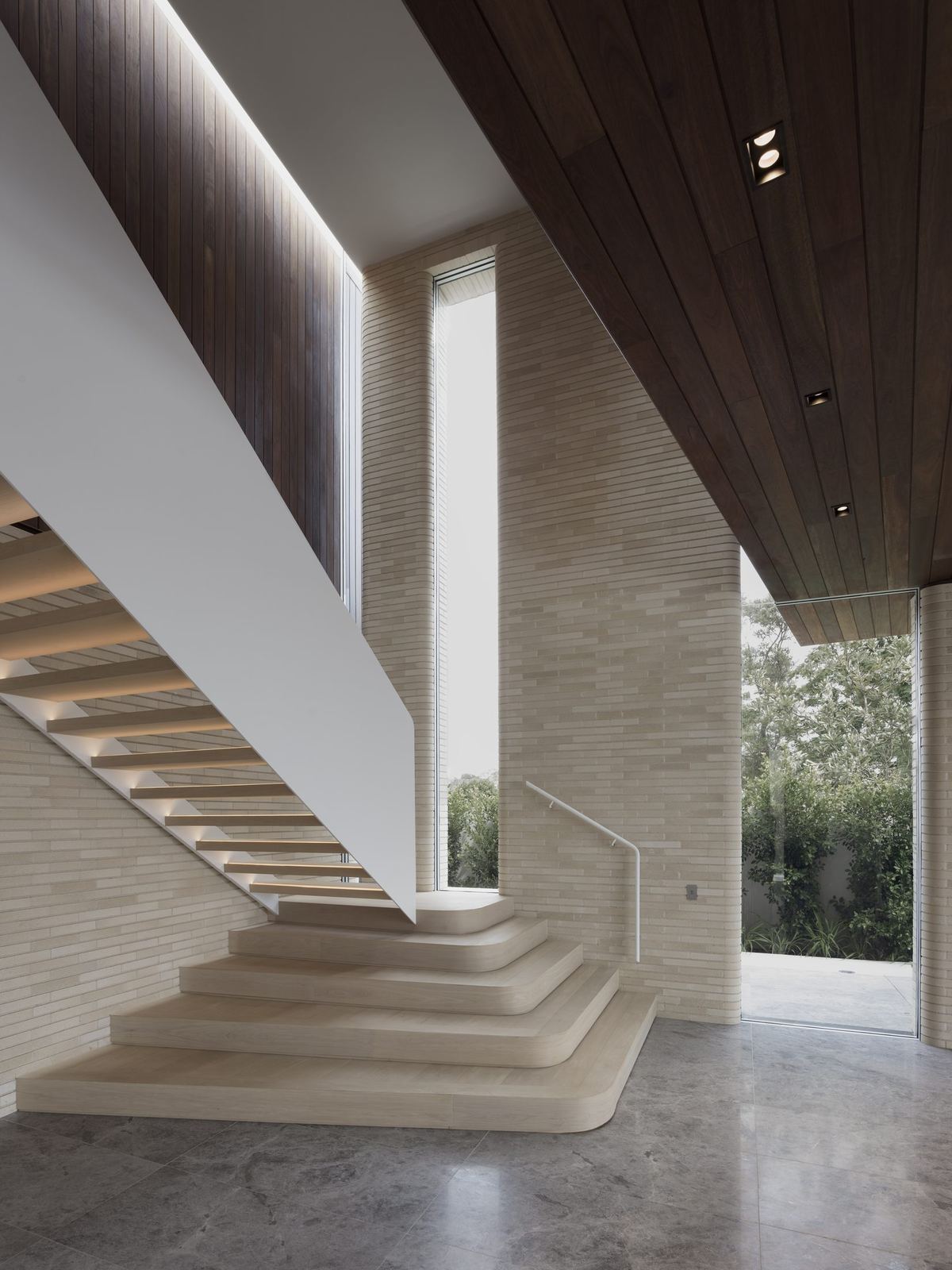 Castlecrag — sculptural travertine staircase beneath timber-lined ceiling with garden glazing, built by HP Constructions with FJC Studio