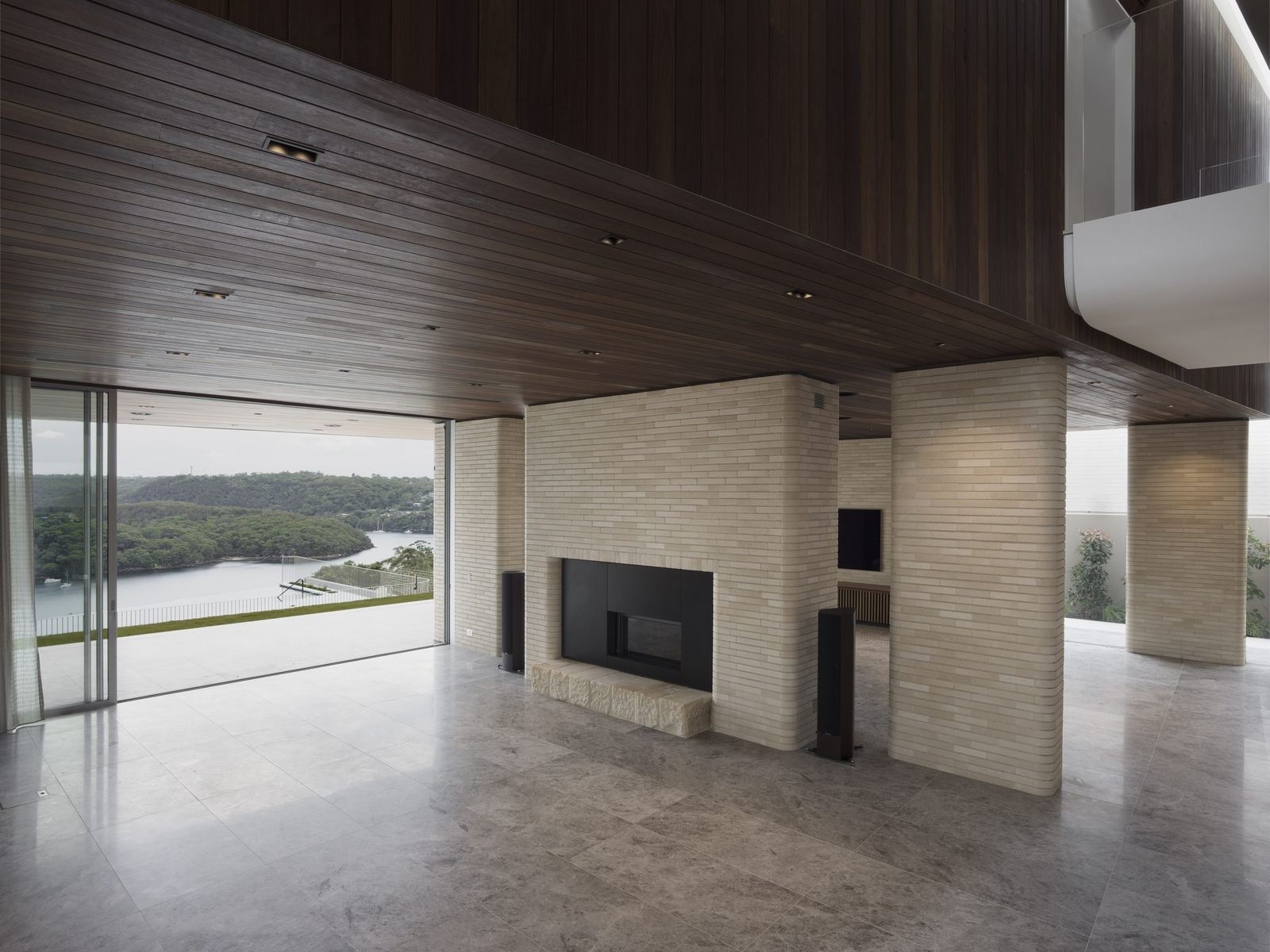 Castlecrag — living room with timber-lined ceiling, stone floor and fireplace facing bushland glazing, built by HP Constructions with FJC Studio