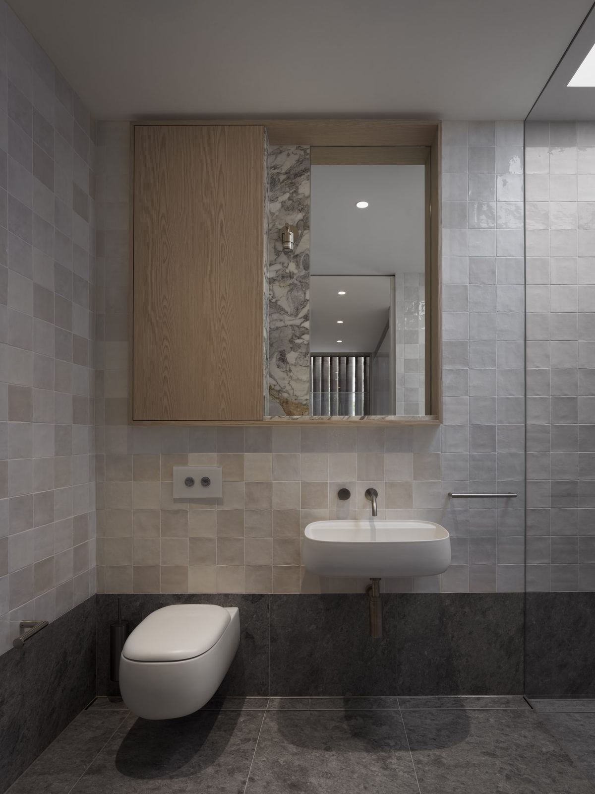 Castlecrag — bathroom with stone-tiled walls, wall-hung toilet and timber-framed mirror, built by HP Constructions with FJC Studio