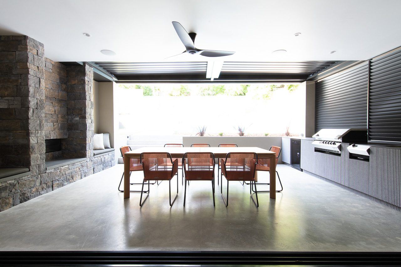 Hunters Hill — covered outdoor room with stacked-stone fireplace, dining table and built-in barbecue, built by HP Constructions with Dale Design Group