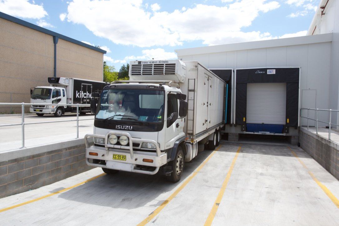 Kitchen Food Company — refrigerated Isuzu truck reversed into a concrete loading dock, built by HP Constructions
