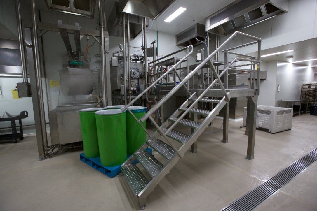 Kitchen Food Company — stainless processing area with elevated platform stairs and green bins, built by HP Constructions