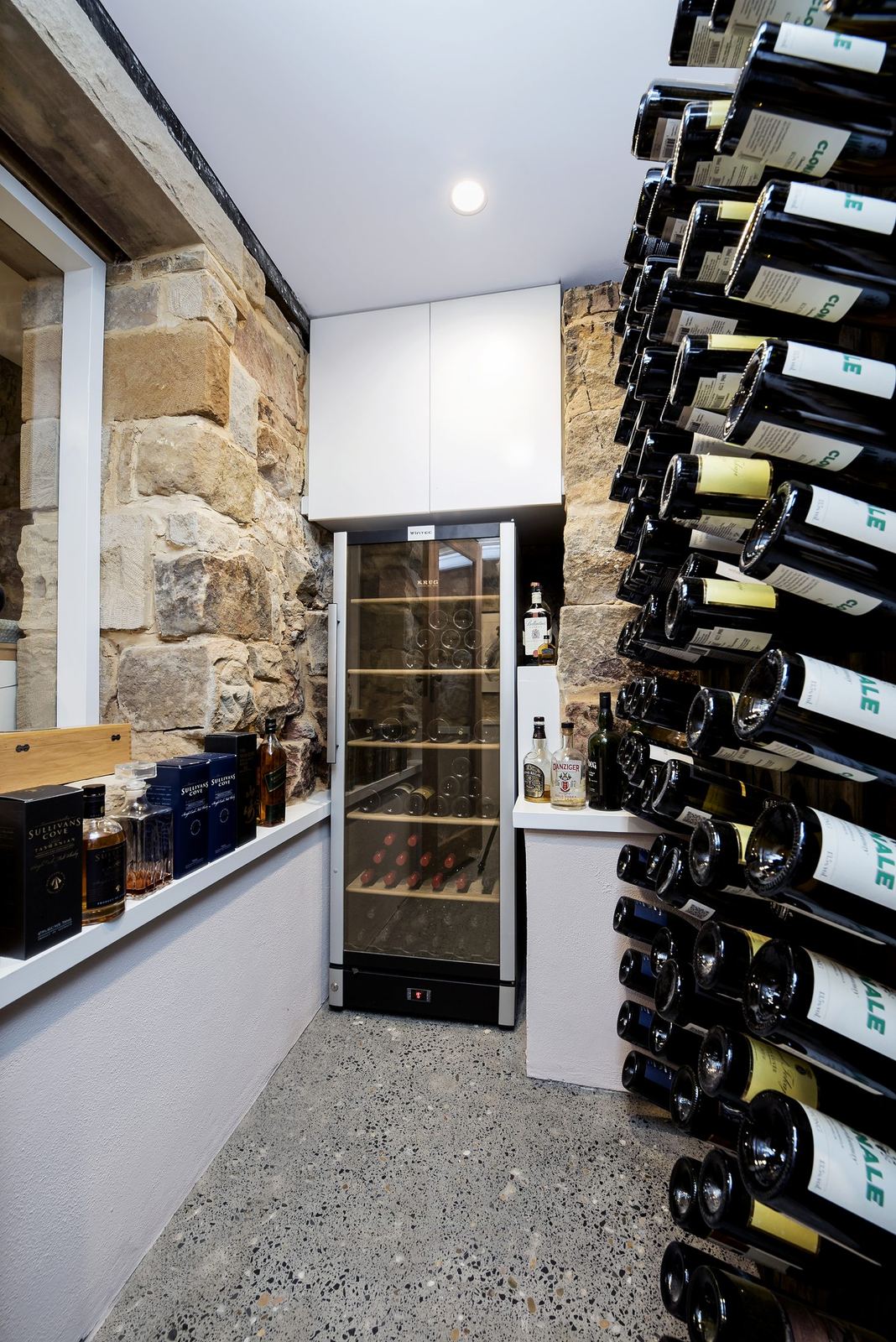 Paddington — wine cellar with wall-mounted racks and exposed sandstone wall, built by HP Constructions with Gutnik Design Group