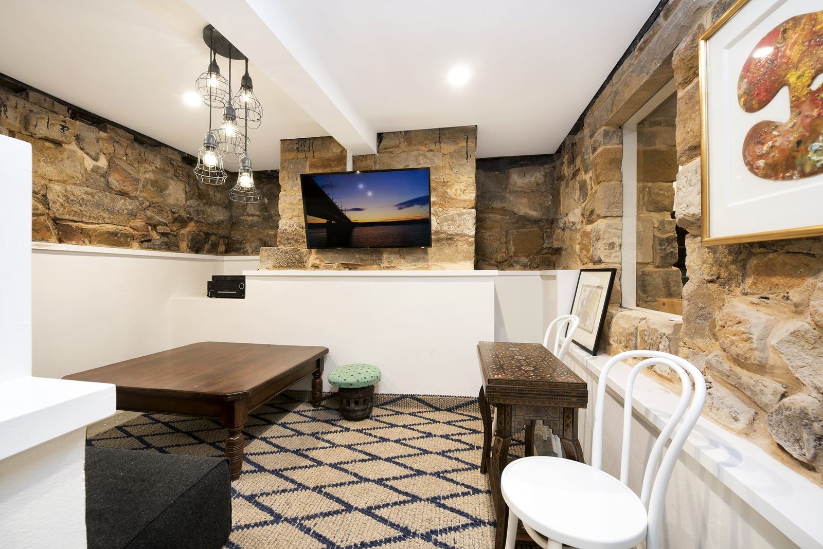Paddington — living room with exposed sandstone walls, mounted television and patterned rug, built by HP Constructions with Gutnik Design Group