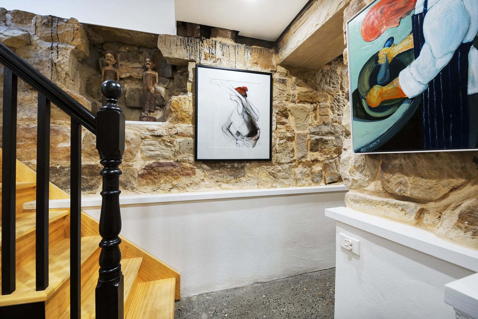 Paddington — staircase with black balustrade, exposed sandstone wall and artwork, built by HP Constructions with Gutnik Design Group