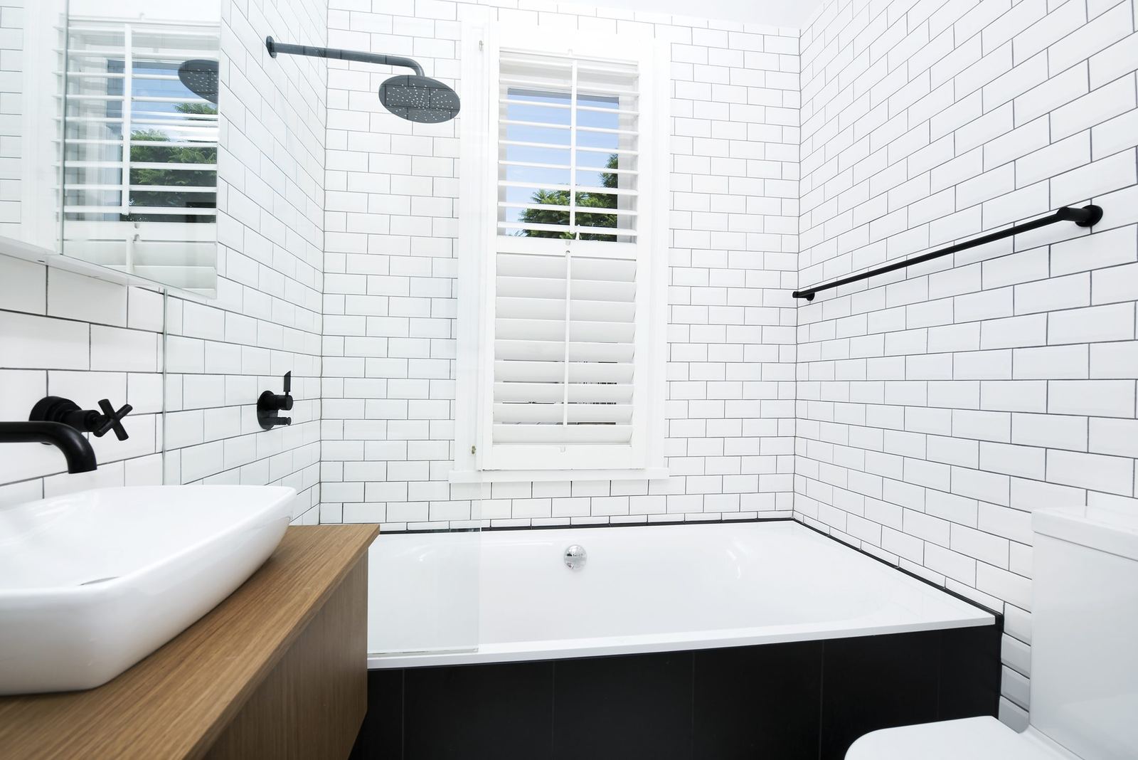 Paddington — bathroom with white subway tiles, black tapware and timber-clad bath, built by HP Constructions with Gutnik Design Group