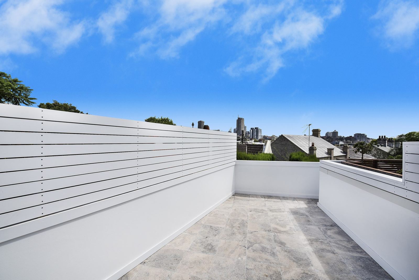 Paddington — rooftop terrace with white slatted screen and distant city skyline, built by HP Constructions with Gutnik Design Group