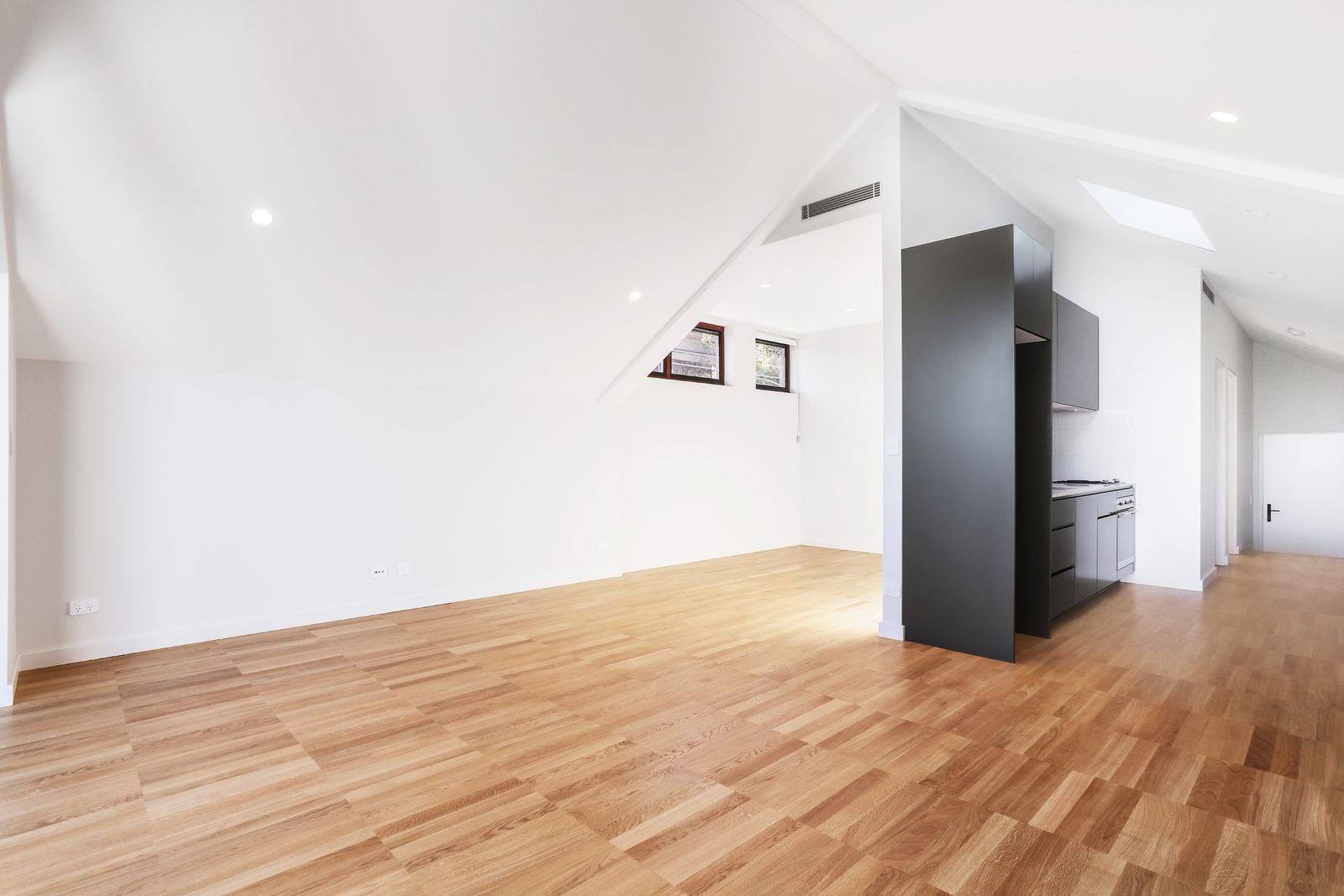 Queens Park Apartments — empty loft room with angled ceiling and black joinery, built by HP Constructions with Ignite Architects