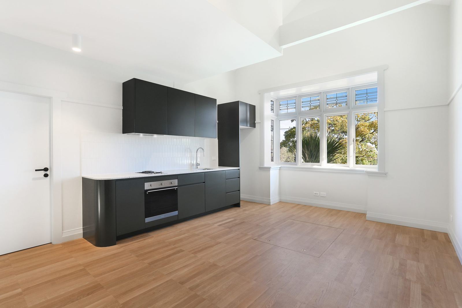 Queens Park Apartments — black kitchen with oven and windows to garden, built by HP Constructions with Ignite Architects