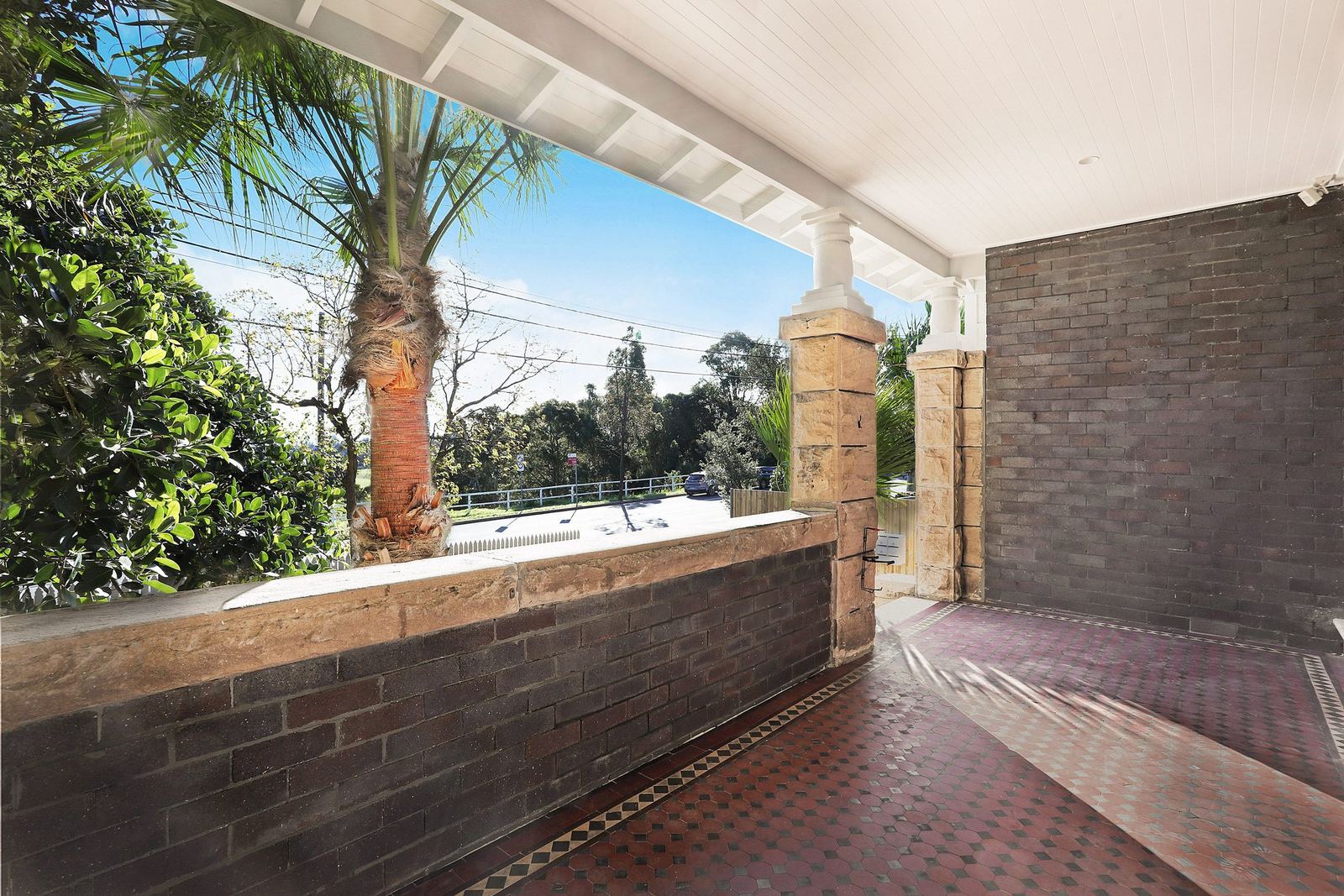 Queens Park Apartments — covered terrace with brick wall and palm tree, built by HP Constructions with Ignite Architects