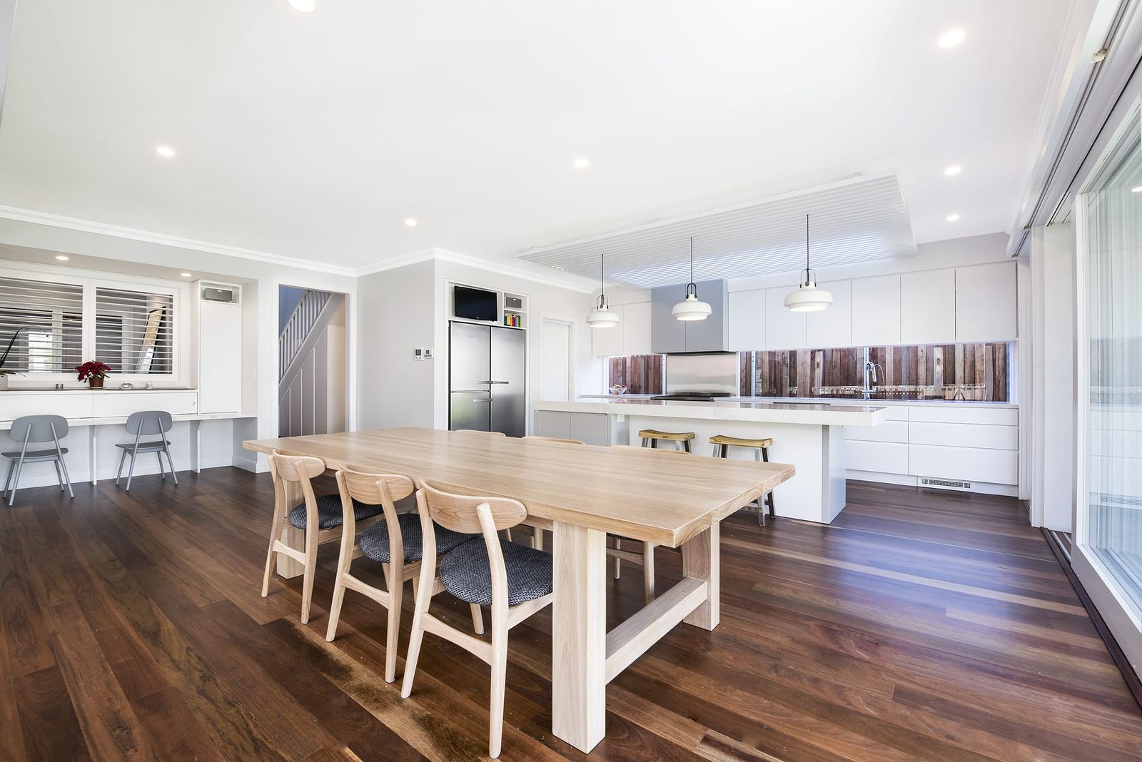 Seaforth — timber dining table beside the open kitchen with pendant lighting, built by HP Constructions with Playoust Churcher