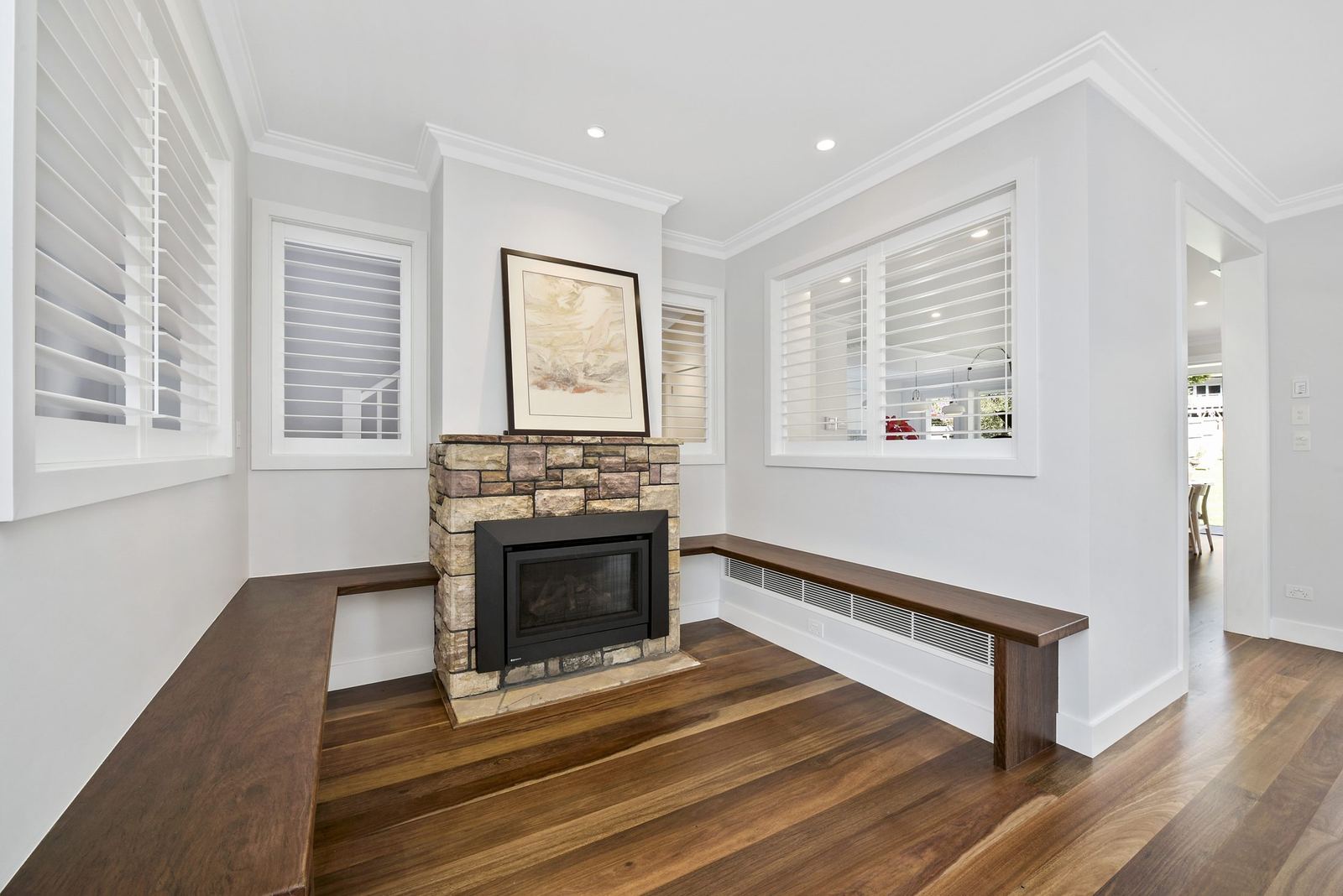 Seaforth — living room with stone fireplace, timber bench seat and plantation shutters, built by HP Constructions with Playoust Churcher
