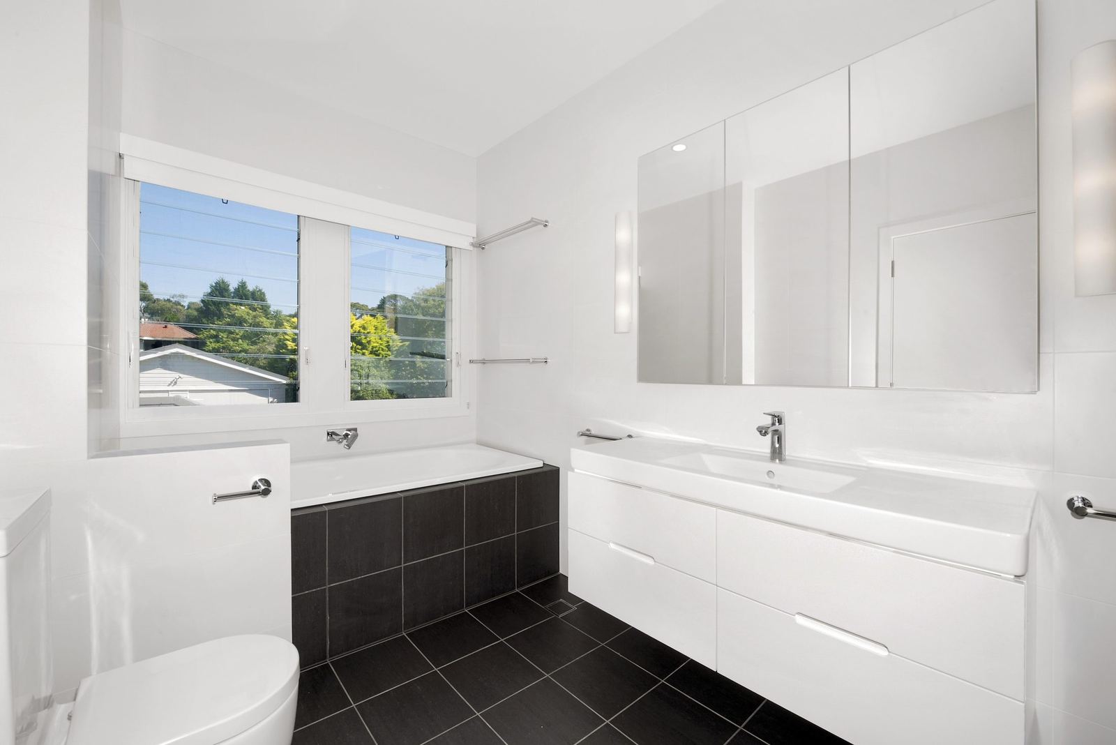 Seaforth — bathroom with white vanity, wall mirror, bath and dark-tiled floor, built by HP Constructions with Playoust Churcher