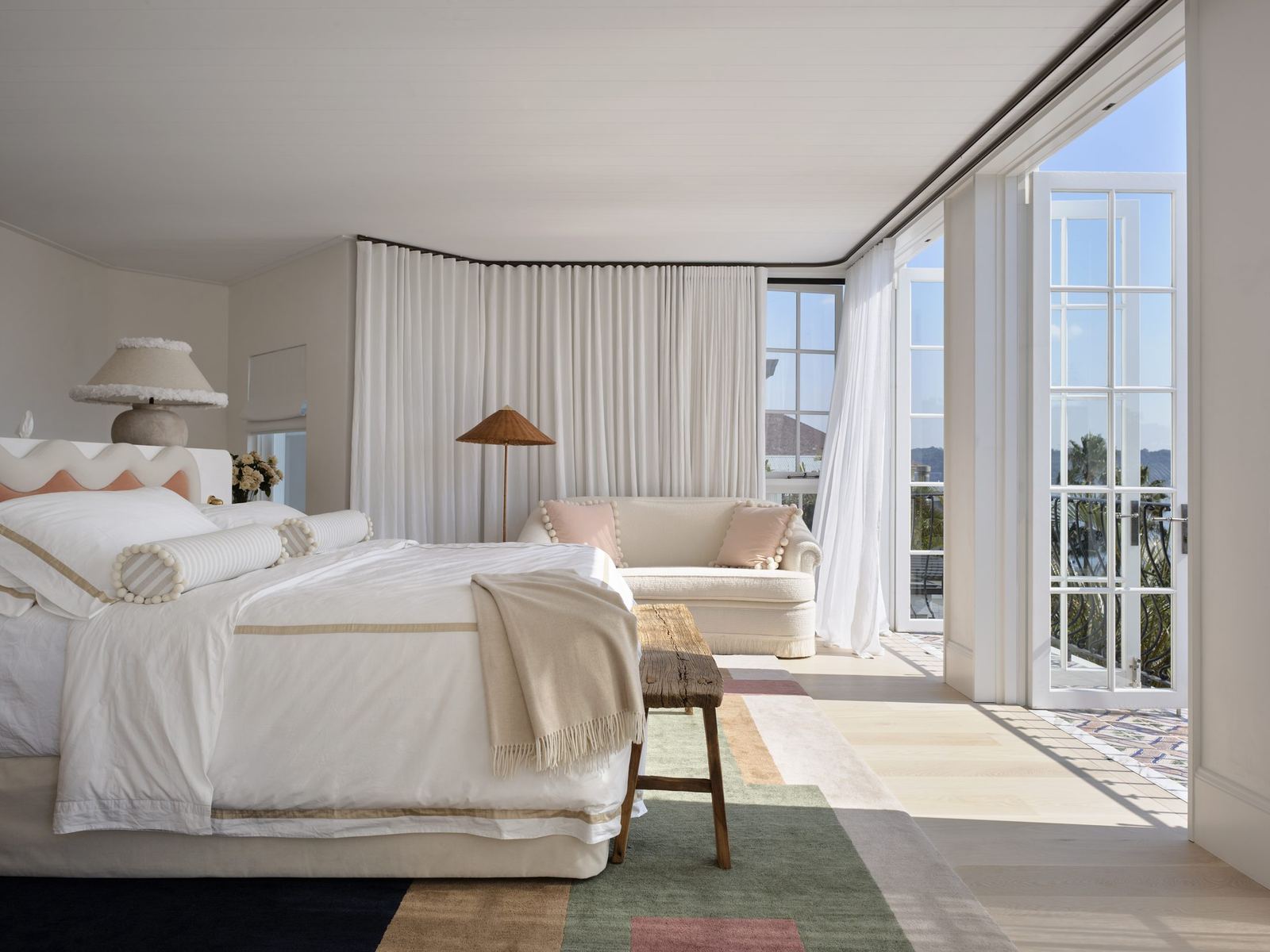 Vaucluse — bedroom with upholstered bed and curtained doors opening to water views, built by HP Constructions with Alexander & Co