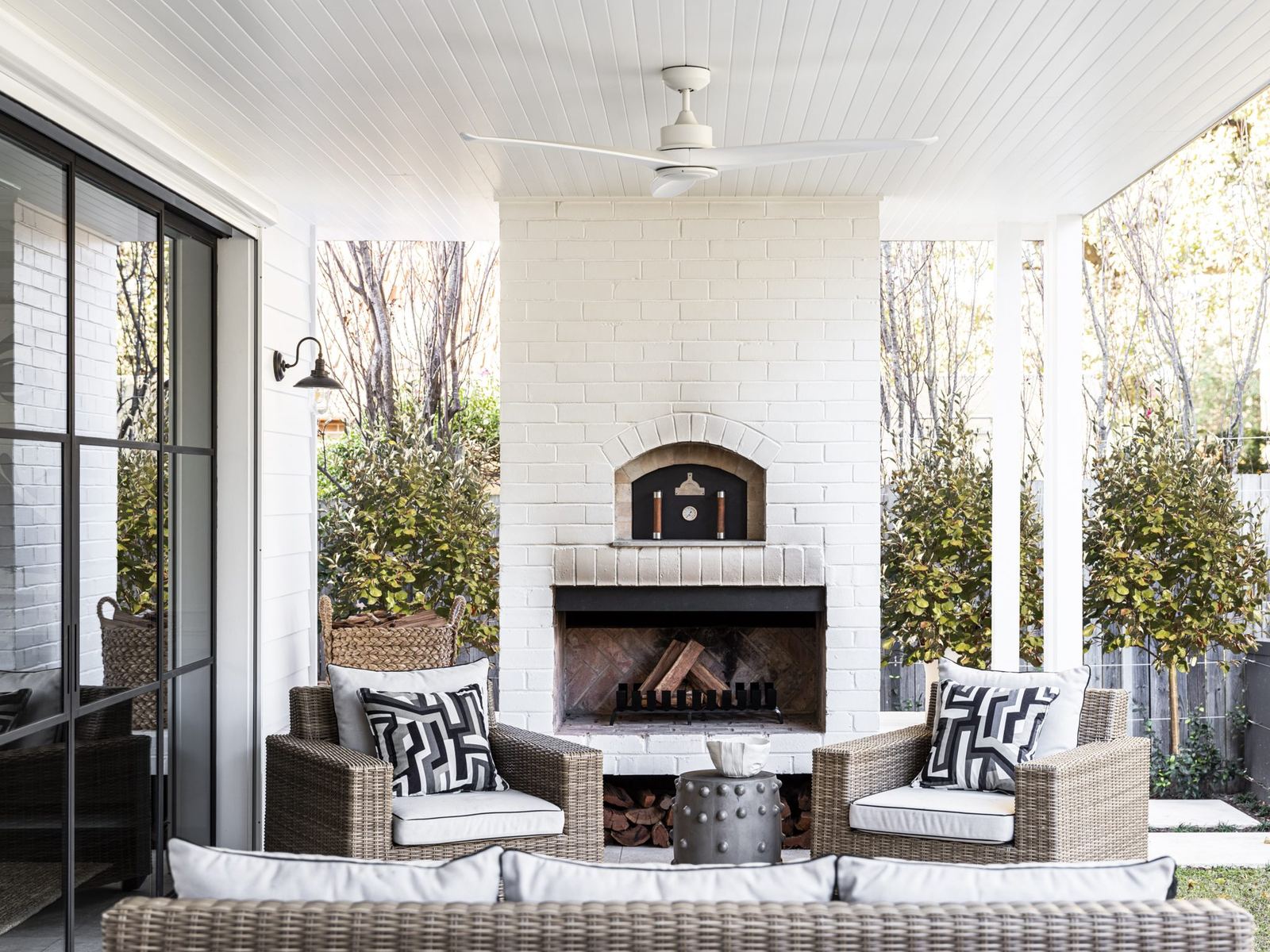 Willoughby — covered outdoor terrace with brick fireplace and wicker lounge, built by HP Constructions with Alexander & Co